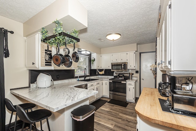 kitchen featuring white cabinetry, kitchen peninsula, appliances with stainless steel finishes, and sink