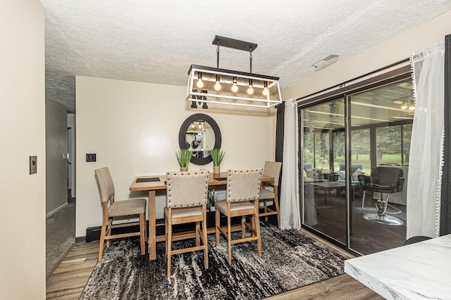 dining space featuring wood-type flooring and a textured ceiling