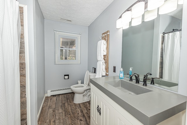 bathroom with vanity, baseboard heating, a textured ceiling, toilet, and hardwood / wood-style floors