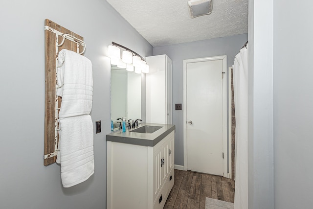 bathroom featuring wood-type flooring, vanity, and a textured ceiling