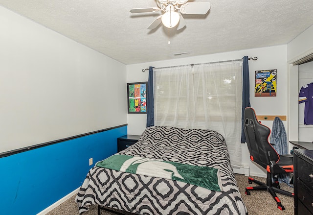 bedroom with a baseboard heating unit, carpet, ceiling fan, and a textured ceiling