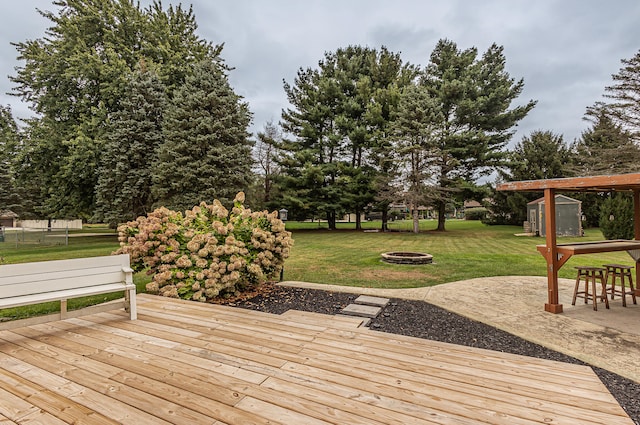 deck featuring a fire pit, a yard, and a storage unit