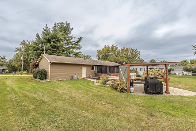 back of house with a lawn, a sunroom, and a patio area