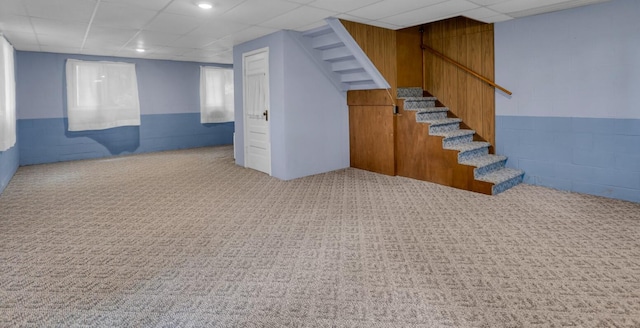 basement featuring a drop ceiling and light carpet