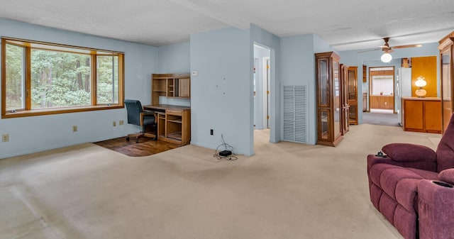 carpeted living room with built in desk, ceiling fan, and a textured ceiling