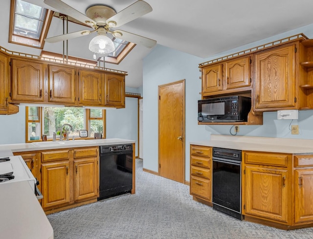 kitchen featuring ceiling fan, vaulted ceiling with skylight, sink, black appliances, and light carpet