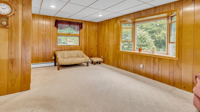 living area with carpet flooring, wood walls, and baseboard heating