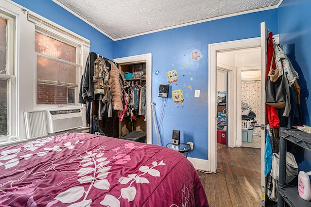 bedroom featuring dark wood-type flooring, a closet, a textured ceiling, cooling unit, and ornamental molding