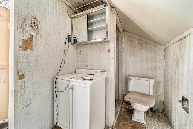 bathroom featuring tile walls, toilet, and washer / dryer