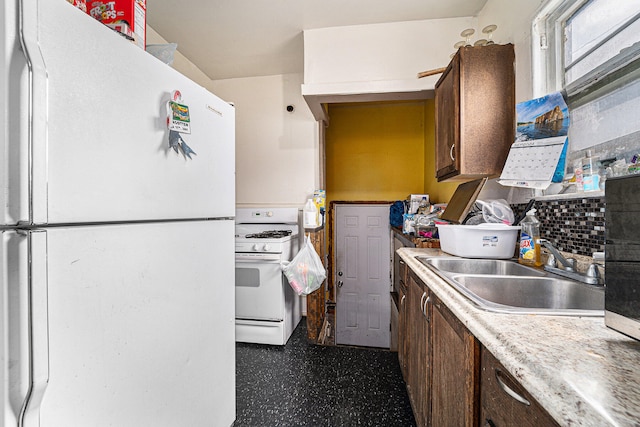 kitchen featuring dark brown cabinets, decorative backsplash, white appliances, and sink