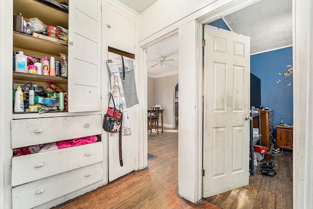 corridor featuring ornamental molding, wood-type flooring, and a textured ceiling