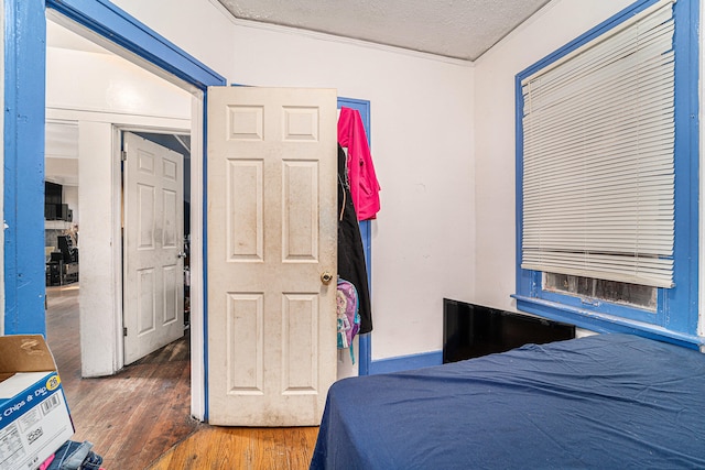 bedroom with ornamental molding, a textured ceiling, and dark wood-type flooring