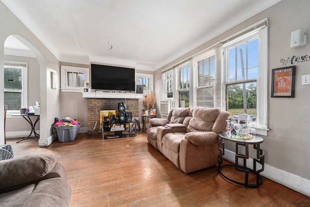 living room with a brick fireplace, plenty of natural light, and wood-type flooring