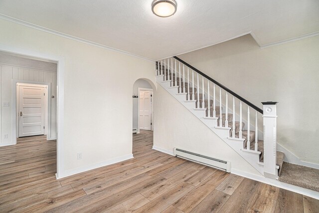 3143 US 31 N, Conway, MI 49722 - staircase featuring hardwood / wood-style flooring, arched walkways, crown molding, and a baseboard radiator