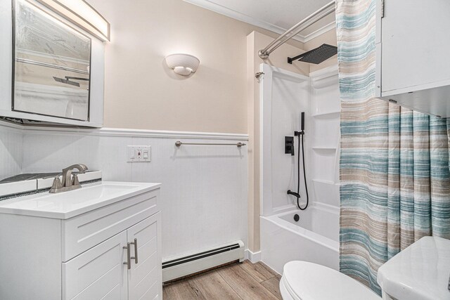 3143 US 31 N, Conway, MI 49722 - bathroom featuring toilet, baseboard heating, a wainscoted wall, shower / bath combo with shower curtain, and wood finished floors