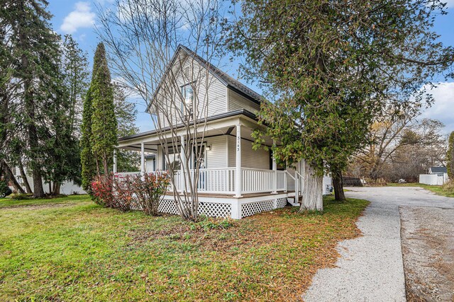 3143 US 31 N, Conway, MI 49722 - view of front facade with aphalt driveway, a front lawn, and a porch