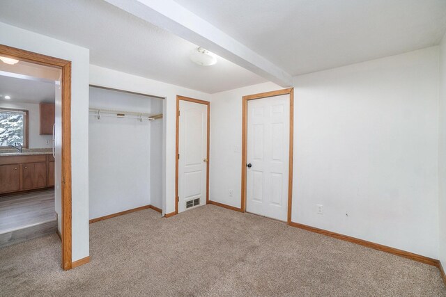 3143 US 31 N, Conway, MI 49722 - unfurnished bedroom with a closet, beam ceiling, light carpet, baseboards, and visible vents
