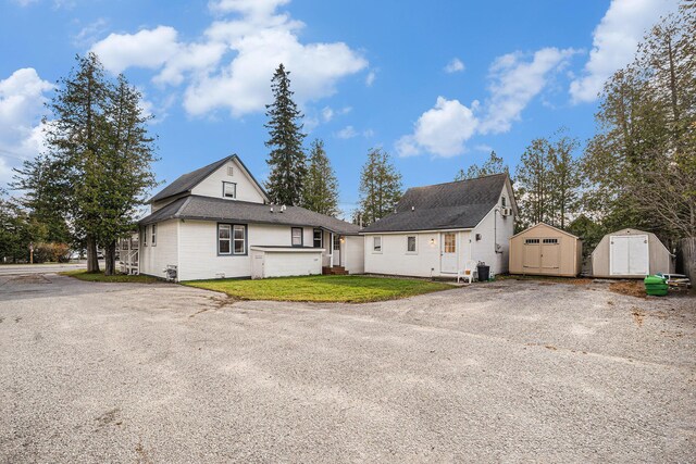 3143 US 31 N, Conway, MI 49722 - view of front facade featuring a storage unit, gravel driveway, an outbuilding, and a front lawn