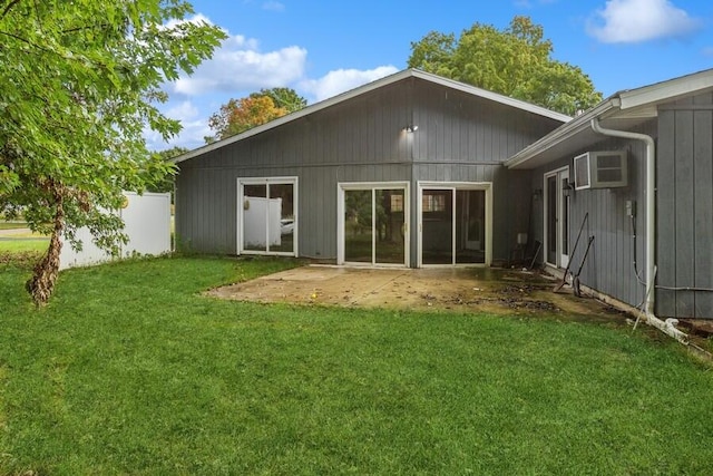 rear view of house with a lawn, a patio, and a wall unit AC