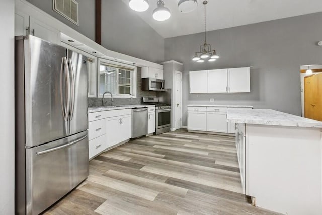 kitchen featuring appliances with stainless steel finishes, decorative light fixtures, light hardwood / wood-style flooring, and white cabinets