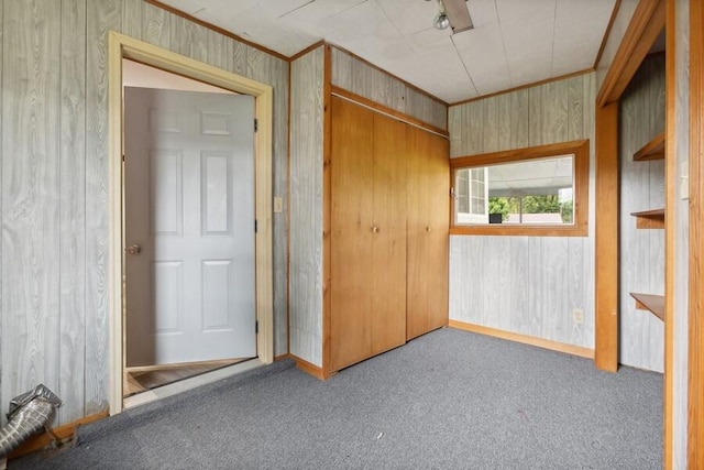 carpeted empty room featuring wood walls