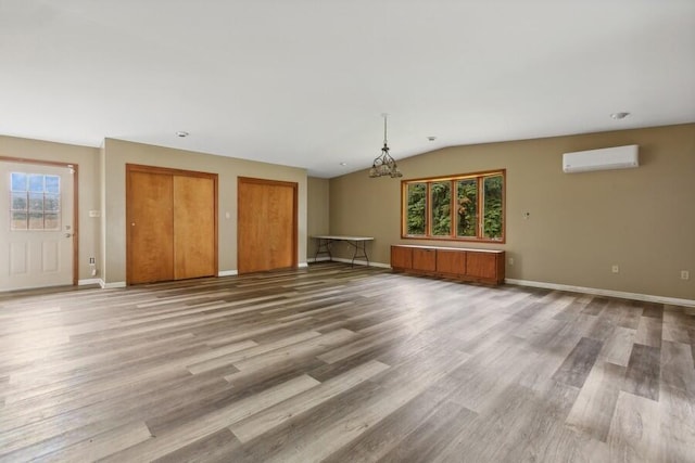 unfurnished living room featuring vaulted ceiling, an AC wall unit, radiator heating unit, wood-type flooring, and an inviting chandelier