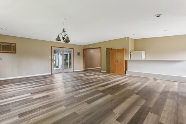 unfurnished living room with lofted ceiling, a chandelier, hardwood / wood-style floors, and a wall mounted air conditioner