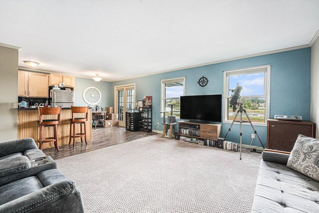 living room with light hardwood / wood-style flooring, a wealth of natural light, indoor bar, and crown molding