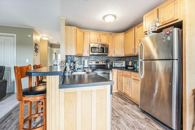 kitchen with light hardwood / wood-style flooring, appliances with stainless steel finishes, sink, and light brown cabinetry