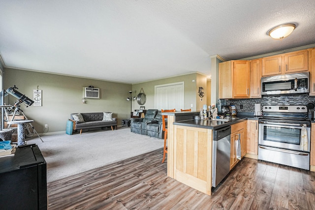 kitchen featuring dark hardwood / wood-style flooring, tasteful backsplash, kitchen peninsula, appliances with stainless steel finishes, and crown molding