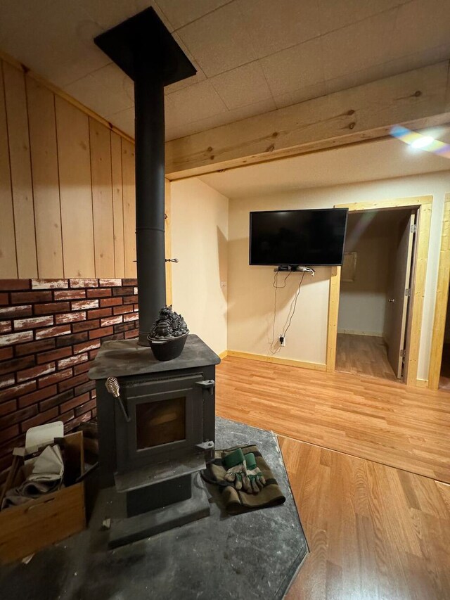 room details with wood walls, a wood stove, and hardwood / wood-style flooring