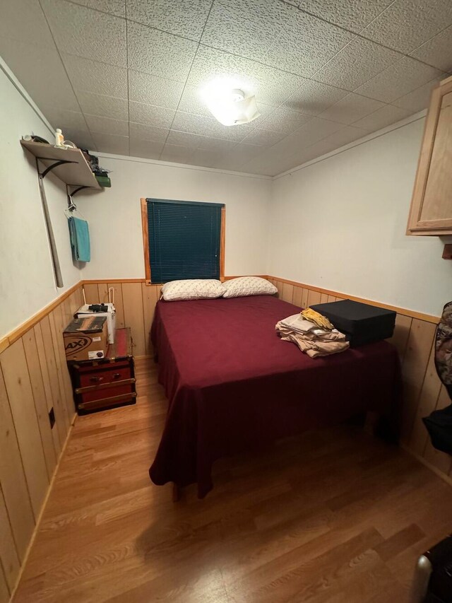 bedroom featuring light hardwood / wood-style flooring and wooden walls