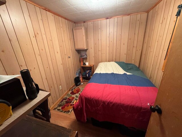 bedroom featuring hardwood / wood-style flooring and wood walls