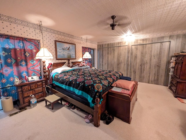 bedroom featuring wood walls, a textured ceiling, ceiling fan, and carpet floors