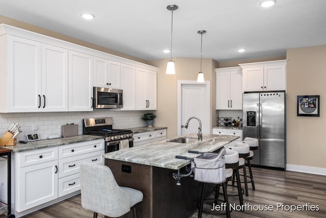 kitchen featuring sink, an island with sink, white cabinets, a kitchen breakfast bar, and appliances with stainless steel finishes