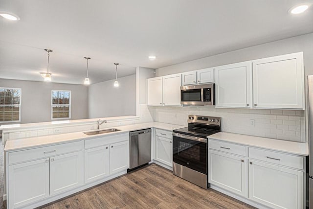 kitchen featuring sink, stainless steel appliances, kitchen peninsula, decorative backsplash, and white cabinets