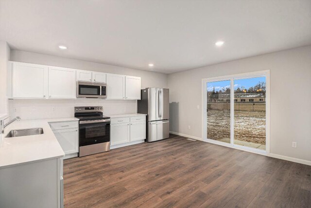 kitchen featuring white cabinets, appliances with stainless steel finishes, dark wood-type flooring, and sink