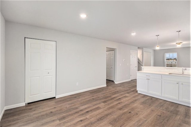 kitchen featuring dark hardwood / wood-style flooring, white cabinetry, sink, and decorative light fixtures