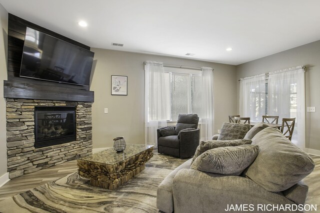 living room featuring a stone fireplace and light hardwood / wood-style floors