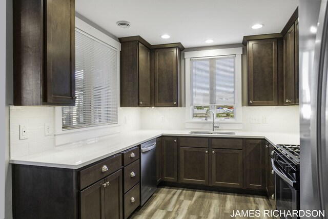 kitchen featuring decorative backsplash, dark hardwood / wood-style flooring, stainless steel appliances, dark brown cabinets, and sink