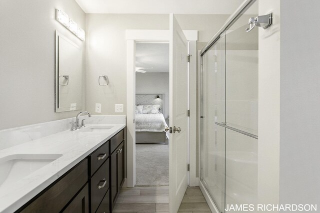 bathroom with wood-type flooring, vanity, and a shower with shower door