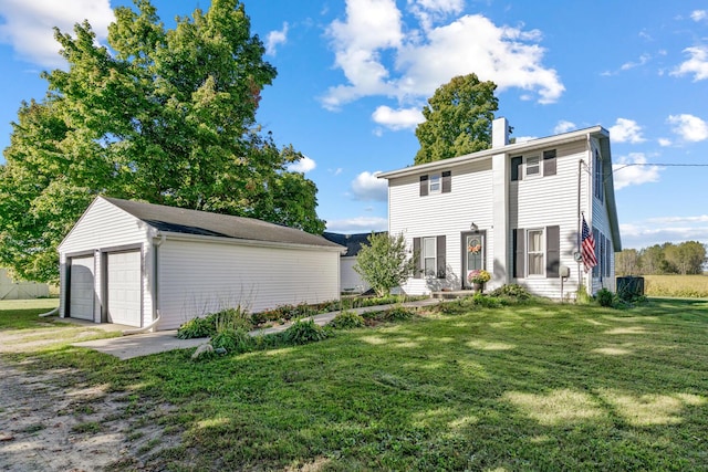 view of front of property featuring a garage, an outbuilding, and a front lawn