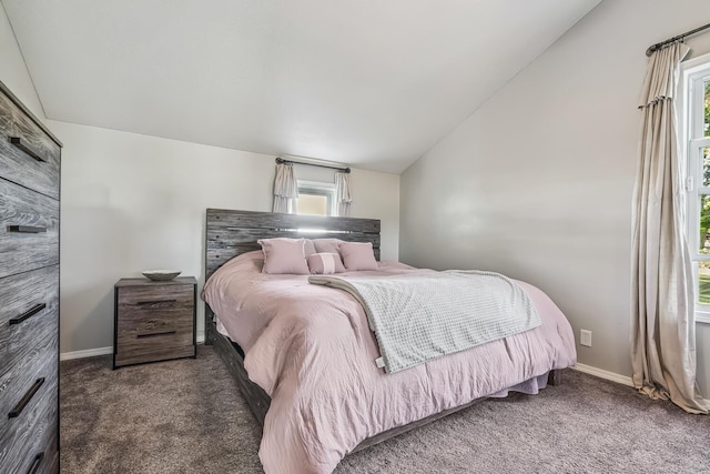 bedroom with dark colored carpet, vaulted ceiling, and multiple windows