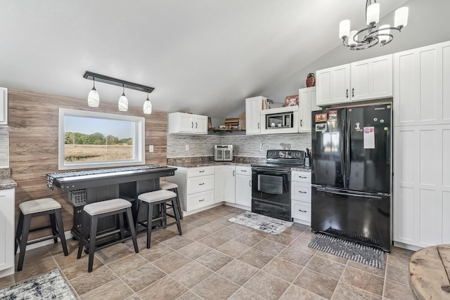 kitchen with black appliances, a kitchen breakfast bar, vaulted ceiling, decorative light fixtures, and white cabinetry