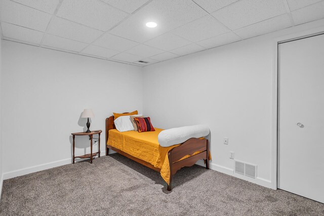 bedroom featuring a drop ceiling and carpet flooring