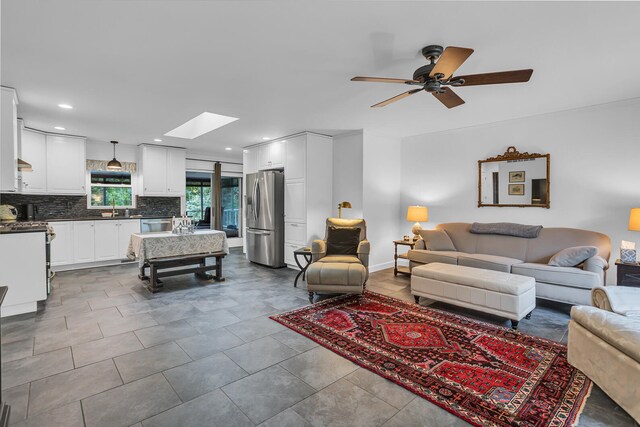 living room with sink, ceiling fan, and a skylight