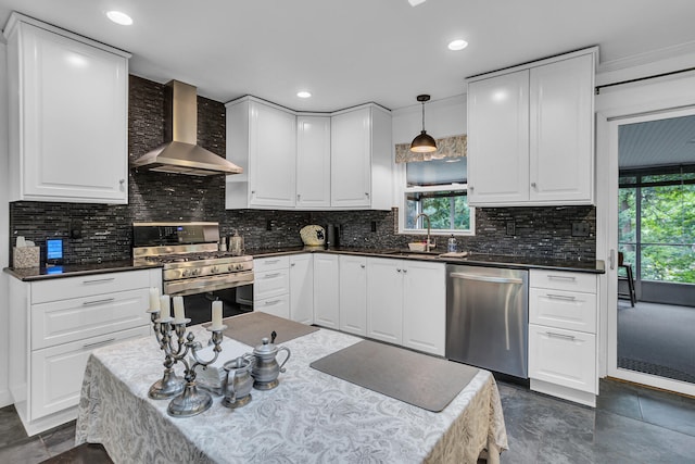 kitchen featuring appliances with stainless steel finishes, hanging light fixtures, wall chimney exhaust hood, and plenty of natural light