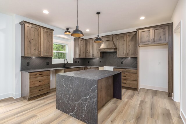 kitchen featuring light hardwood / wood-style flooring, hanging light fixtures, sink, and a kitchen island