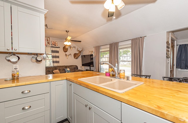 kitchen featuring ceiling fan, sink, kitchen peninsula, gray cabinets, and wood counters