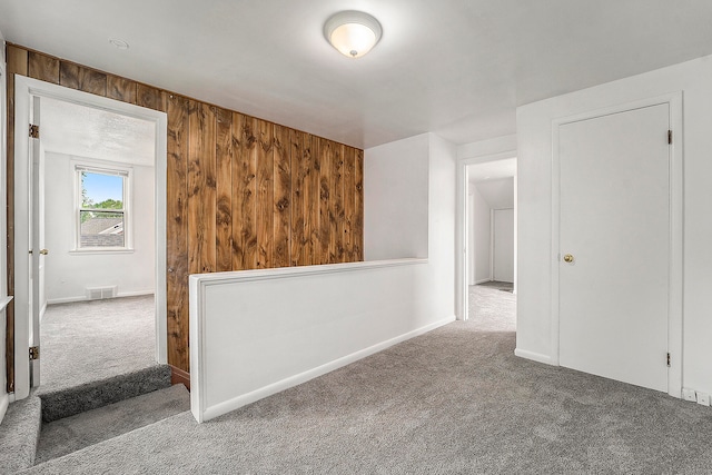 unfurnished room featuring carpet floors and wooden walls